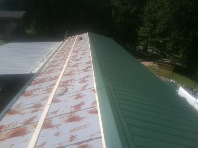 Old rusted panels beside newly installed green metal roofing — Wind Damage Roof Repair by Roofing Brothers in Cornwall Bridge