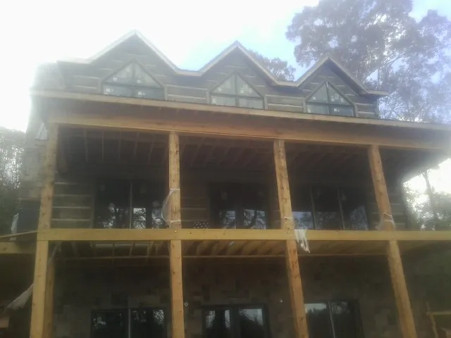 Dormers and porch framing on a large log home under construction — Roof Coating work by our crew in Cornwall Bridge
