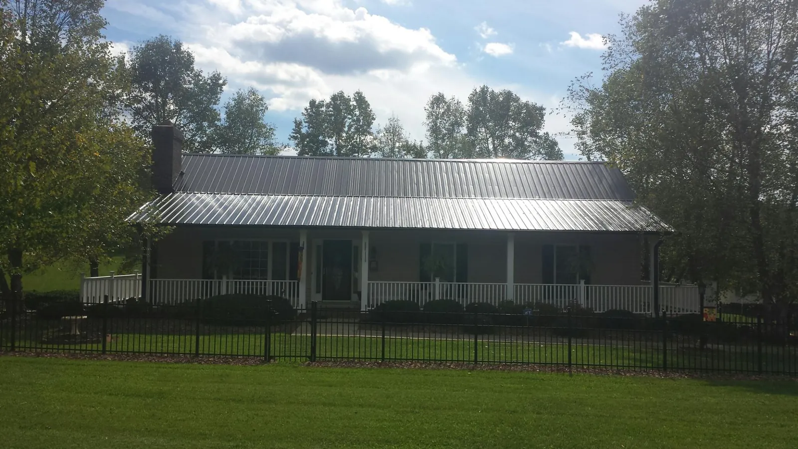 Gray metal roof on a brick ranch with a full width front porch — Gutter Guard Installation work by our crew in Cornwall Bridge