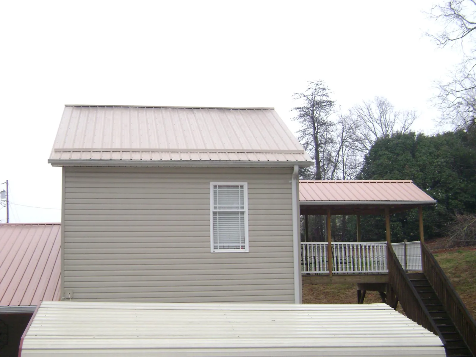 Tan metal roofs on a two story addition and attached porch, from a Roof Replacement job in Cornwall Bridge