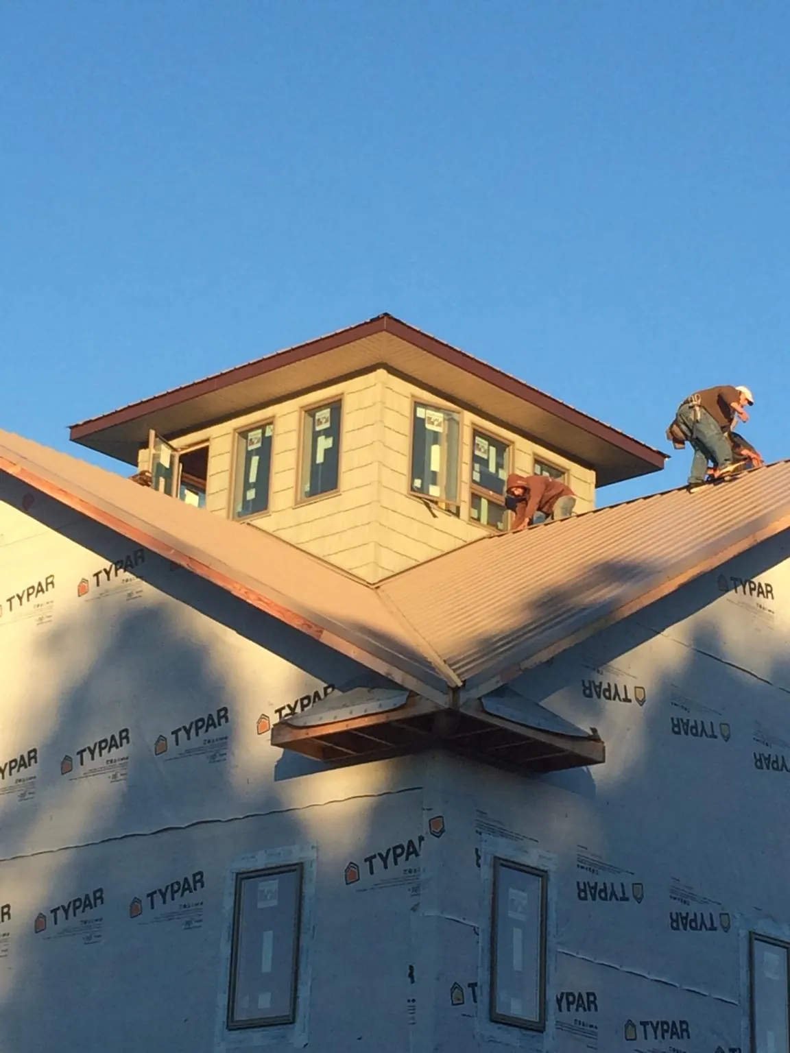 Roofers working around a rooftop cupola on a new metal roof at sunset — Roof Waterproofing in Cornwall Bridge by Roofing Brothers